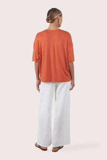 Back view of the Yara Top Orange highlighting the garment shape and drape.