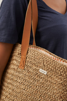 Minimal strap detail on beach bucket straw bag designed for effortless resort styling