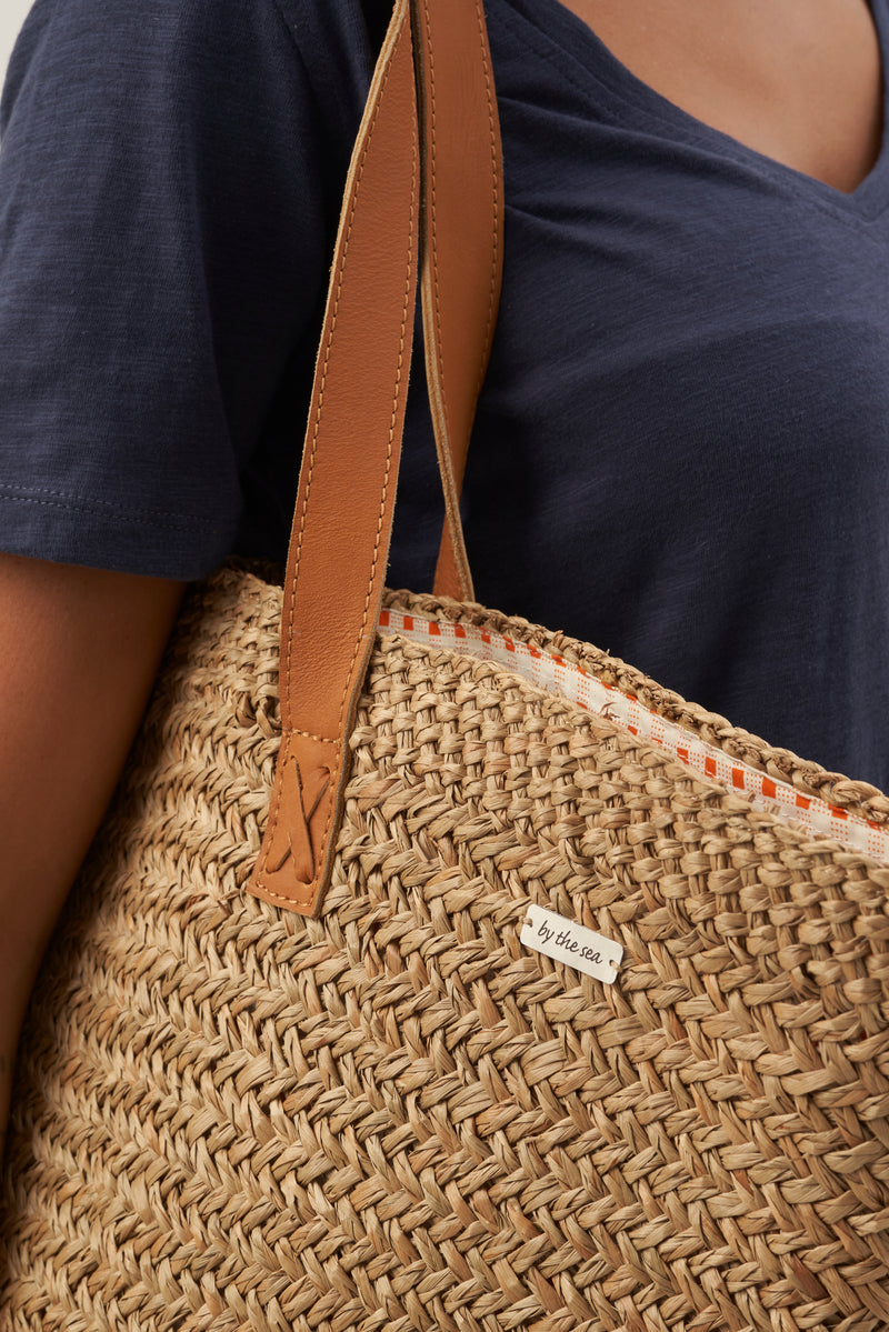 Minimal strap detail on beach bucket straw bag designed for effortless resort styling