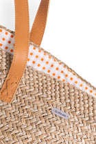 Angled view of the Natural Straw Tote Bag revealing its refined construction and elegant details